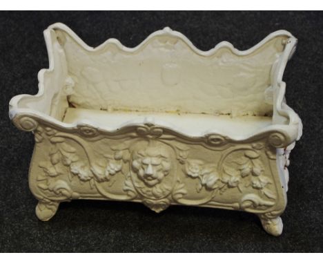 A painted cast iron planter decorated with lion masks and foliage