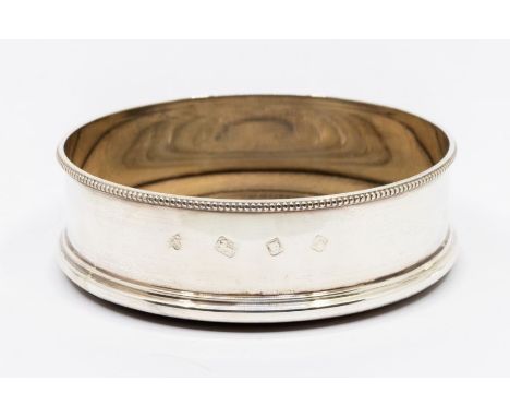 A Modern plain silver wine coaster with beaded border, turned wooden base, hallmarked by A Chick &amp; Sons., London, 1972, 1