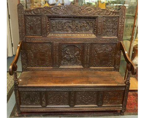A 17th century and later oak marriage bench / settle, the pannelled back and seat carved with Coats of Arms, Biblical scenes 