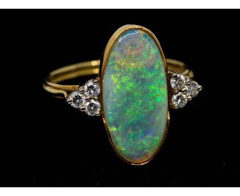 An opal and diamond 18ct gold ring, comprising an elongated oval opal length approx. 18mm x 8mm, green and pale blue play of 