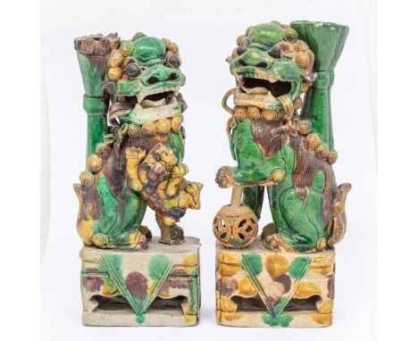 A pair of Chinese egg and spinach glazed Dogs of Fo incense (jos stick) holders, Qing Dynasty (18th/19th Century), the female