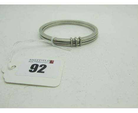 A Modern Hallmarked Silver Bangle, composed of three plain bangles joined by three bars with inset highlights. 