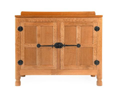 Workshop of Robert Mouseman Thompson (Kilburn): An English Oak Panelled Drinks' Cupboard, with raised upstand over two cupboa