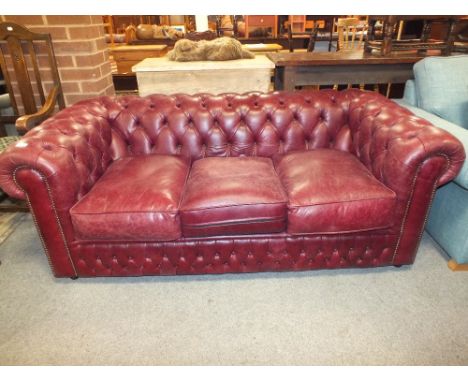 AN OXBLOOD LEATHER STYLE THREE SEATER SOFA