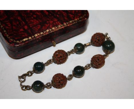 A CARVED WOOD AND JADE TYPE BRACELET