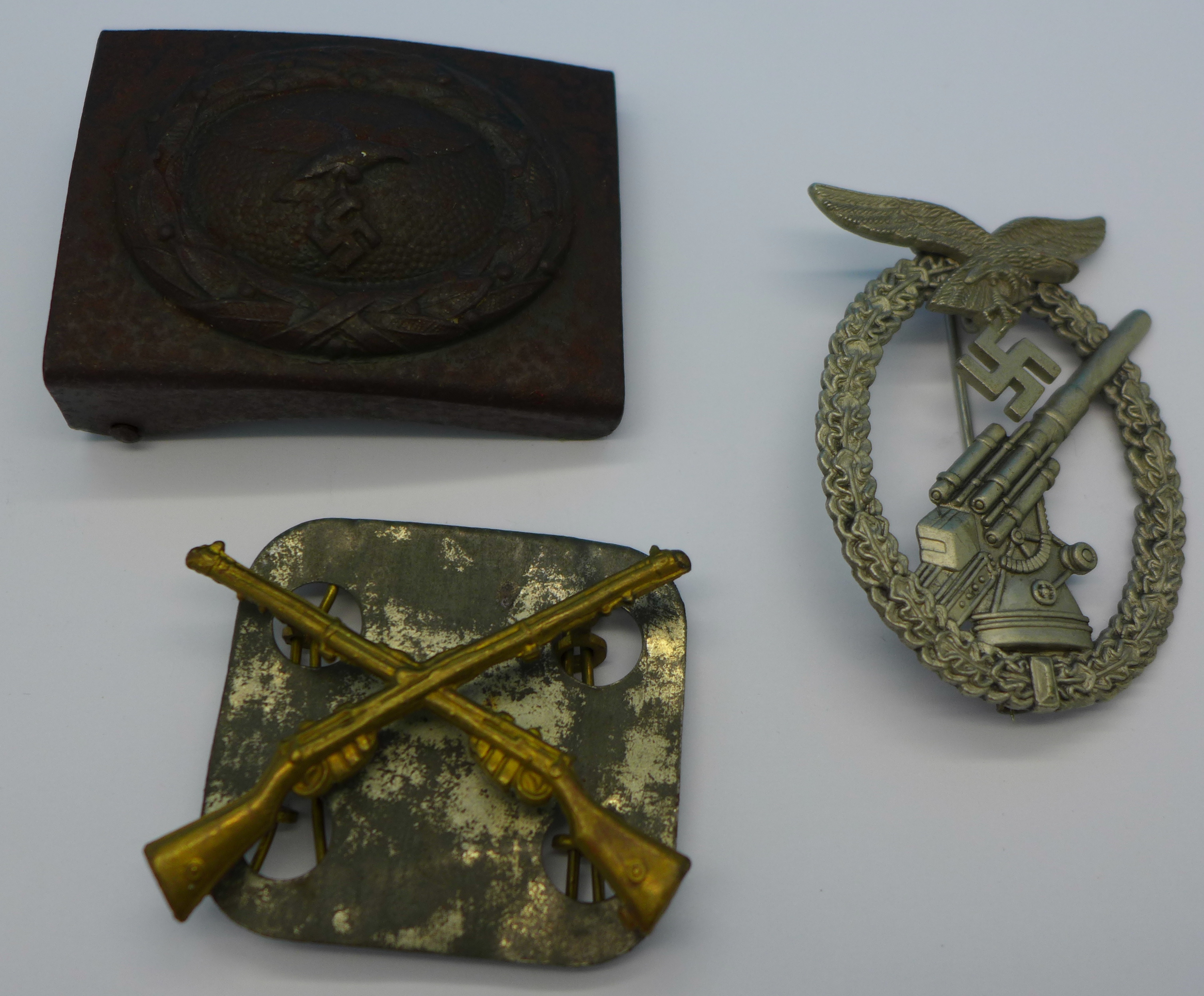 A military cap badge with crossed rifles, a replica German badge and a ...