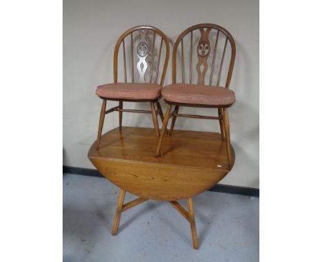 An Ercol elm and beech drop leaf kitchen table together with a pair of chairs 