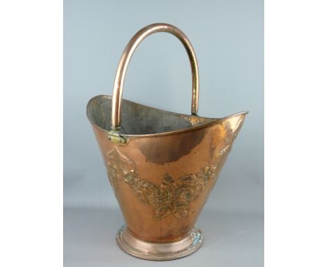 A COPPER HELMET SHAPED COAL SCUTTLE with raised floral decoration, 54 cms high overall