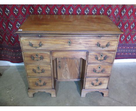 A good quality Georgian mahogany desk with a slide above seven drawers and a central cupboard raised on bracket feet with a g