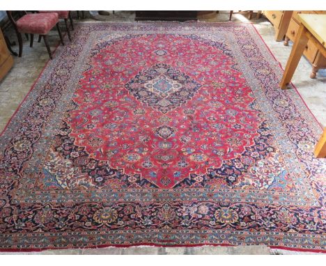 A hand knotted large Kashan rug with red ground central field and blue ground border, approx 374cm x 290cm - overall in good 