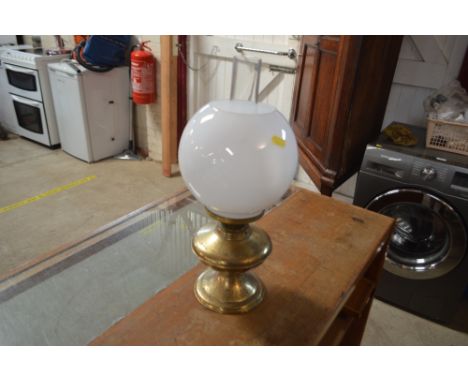 A brass oil lamp with opaque glass shade