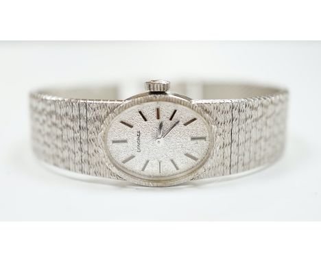 A lady's late 1950's 9ct. white gold Longines manual wrist watch, with integral 9ct white gold bark effect bracelet, gross we