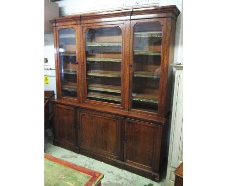 LIBRARY BOOKCASE, early Victorian mahogany with three glass doors enclosing leather trimmed shelves of three panel doors on a