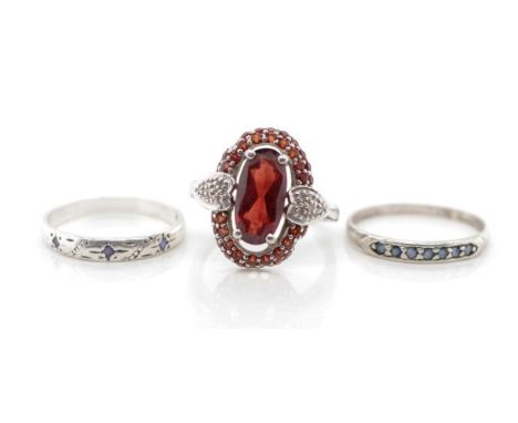 A group of three sterling silver gem set rings includes garnet and sapphire examples. Approx total weight 8 grams, ring size 