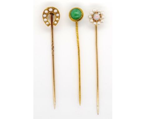 A group of three gold and gemstone stick pins includes a pearl set horse shoe, a white opal with a white pearl surround, as w