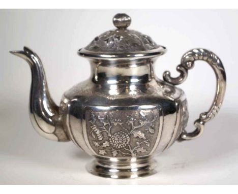 Early 20th century Chinese silver teapot with raised and engraved decoration depicting flowering plants, 18.5cm wide, 14.5cm 