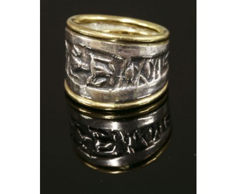 A silver and gold tapered band ring,by Patricia Ann Fruttauro, with a deeply textured central silver section with gold guards