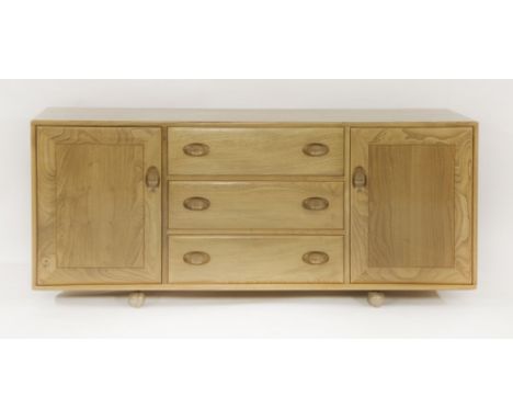 An Ercol ash low sideboard, 1970s, with three central drawers flanked by cupboards, on castors, labelled and dated 1978,156cm