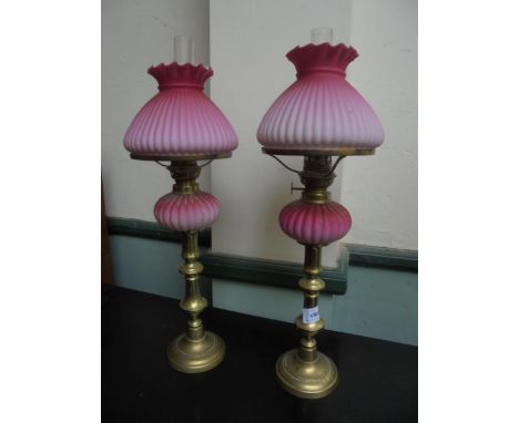 A neat pair of candlestick styled oil lamps with pink oil container and shades with funnels.