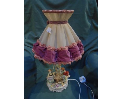 Continental decorated table lamp with figurines on sea-saw marked hand paind M with crown over, made in GDR