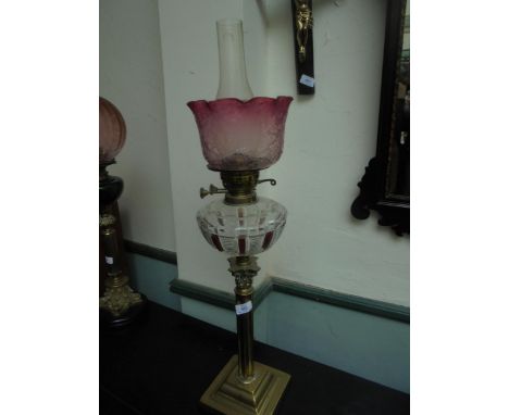 A fine brass single oil lamp, column design with cut glass oil holder and cranberry styled glass shade with funnel.