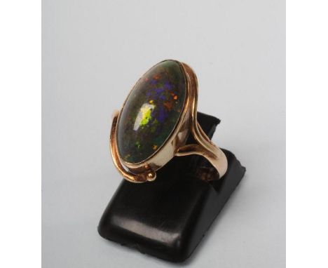 AN OPAL RING, the oval cabochon polished green stone in an art nouveau style rub-over setting to a plain shank, stamped 14k, 