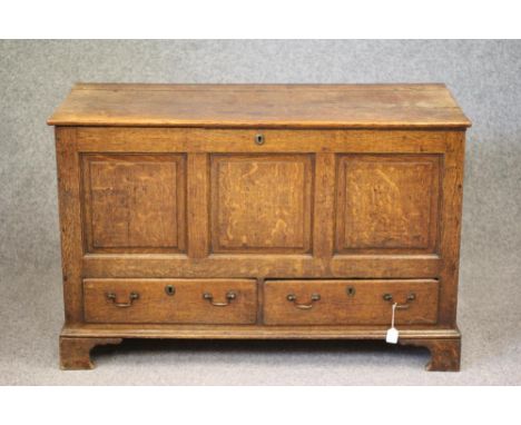 AN OAK PANELLED CHEST, late 18th century, the hinged plank lid opening to a void interior, the fascia with three fielded pane