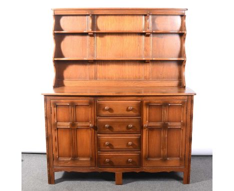 Ercol elm dresser, panelled back with two fixed shelves, the base with four central drawers flanked by doors, width 147cm, de