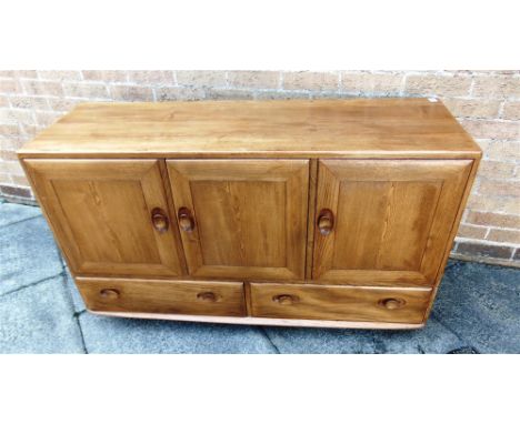 AN ERCOL LIGHT ELM SIDEBOARD  fitted with three doors above pair of drawers, 130cm wide 44cm deep 76cm high