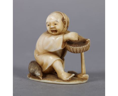 A LATE 19TH CENTURY JAPANESE IVORY NETSUKE of a woodworker, kneeling, his adze beside him and holding a basket of rice, start