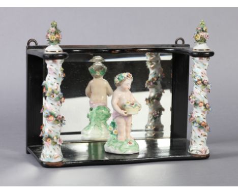 A GERMAN PORCELAIN AND MIRROR LINED EBONISED WALL SHELF, the uprights of floral encrusted and entwined decoration with finial