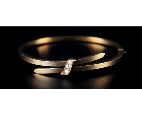 A LATE VICTORIAN STIFF HINGED BANGLE IN 9CT GOLD, the square section crossover front joined by a scroll with Old European eig