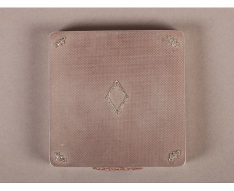 AN ENGLISH ENGINE TURNED SILVER COMPACT of rounded square form, the hinged lid applied with diamond set open lozenge and shap