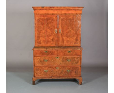 AN 18TH CENTURY FIGURED AND CROSSBANDED FIGURED WALNUT CLOTHES PRESS inlaid with herringbone banding, having a cavetto and cu