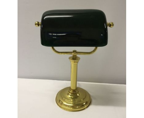 A brass desk light with green glass shade