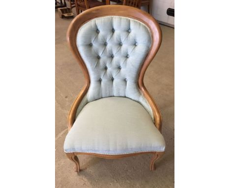 A light wood framed nursing chair with pale blue upholstery.