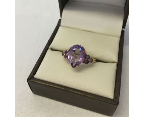 A 9ct gold dress ring set with a large pear cut amethyst and amethyst set shoulders. Size approx O½, total weight approx 2.5g