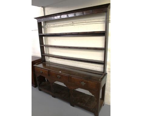 George III oak dresser, the open shelf back above three drawers and a three bay base with pot shelf, on shaped stile supports