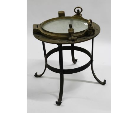 Large brass porthole cover adapted for use as an occasional table on a wrought iron stand, 50 x 60cm overall