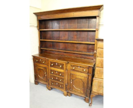 Early 19th Century elm and mahogany dresser, the boarded shelf back above a breakfront with moulded top, the base with an arr