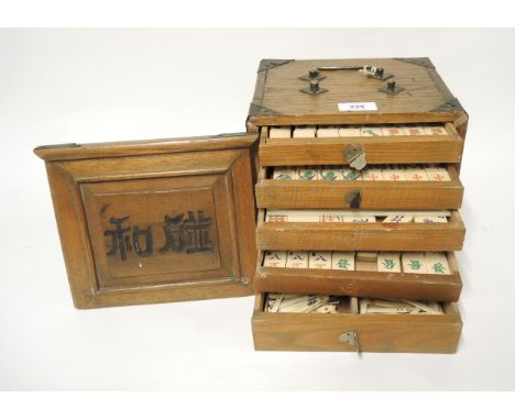 Early 20th Century oak cased mahjong set, the case with silver plated mounts, the sliding door enclosing five drawersThere ap