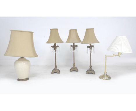 A group of five table lamps, comprising a set of three brass effect lamps with glass drops and caramel coloured shades, each 