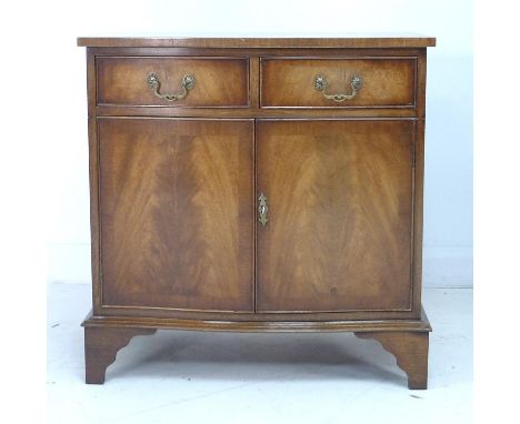 A reproduction mahogany veneered serpentine fronted cabinet, in the Regency style, with two drawers over two cupboard doors e