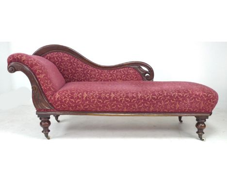 A late Victorian mahogany chaise longue, floral carved frame, upholstered in red and gold coloured fabric, raised on turned l