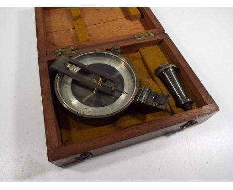 An early 20th century surveyors compass in cloth lined wooden travel case with metal tripod attachment. The compass is in goo