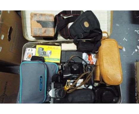 A vintage suitcase containing a quantity of vintage cameras and accesories to include a Pentax Asahi Spotmatic, a Pentax P30N