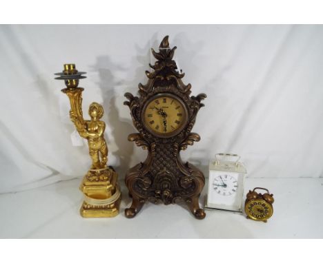 Three clocks comprising a decorative bronze style clock, a carriage clock and a travel alarm clock, also included small table