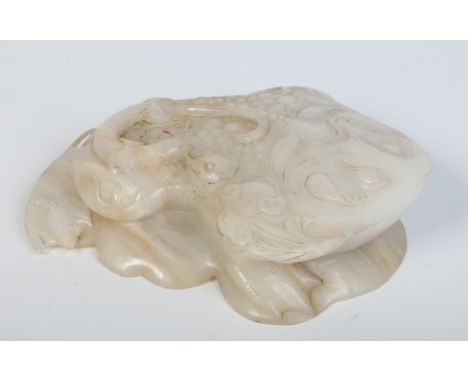 A Chinese carved white jade model of a horned toad raised on a ruyi branch, with a lizard upon its back and each creature hol