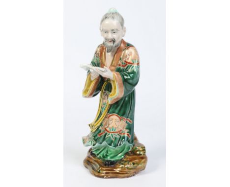 A 20th century Chinese figure decorated in famille vert enamels and modelled as a scholar stood reading a text, 29cm. Conditi