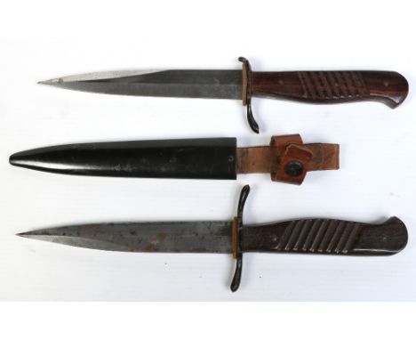 A World War I German trench knife with wooden scales, metal scabbard and leather frog, along with another bare example. Blade